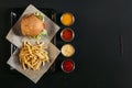 top view of french fries with delicious burger on tray and assorted sauces Royalty Free Stock Photo